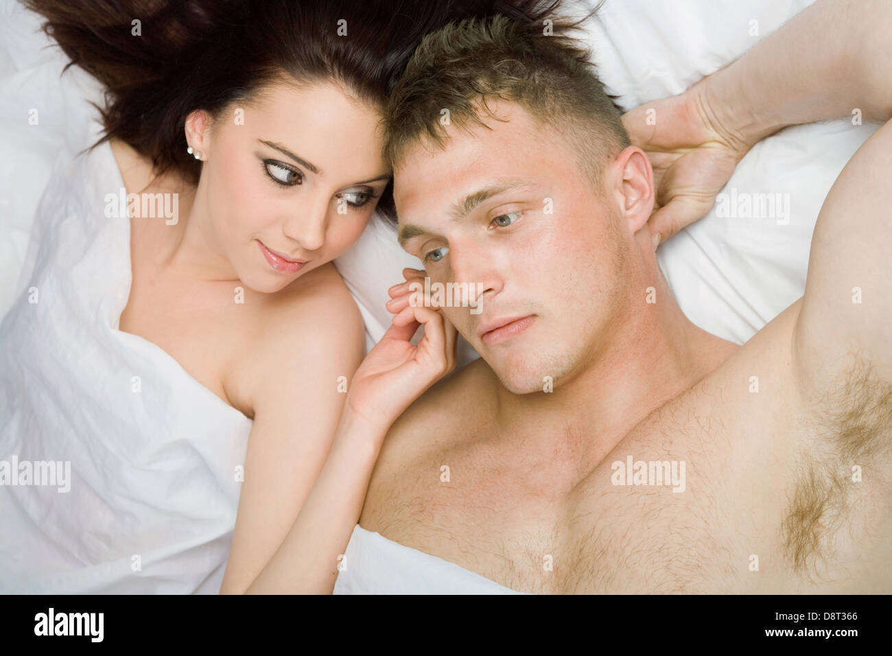 A young couple lying down in bed viewed from overhead. Stock Photo