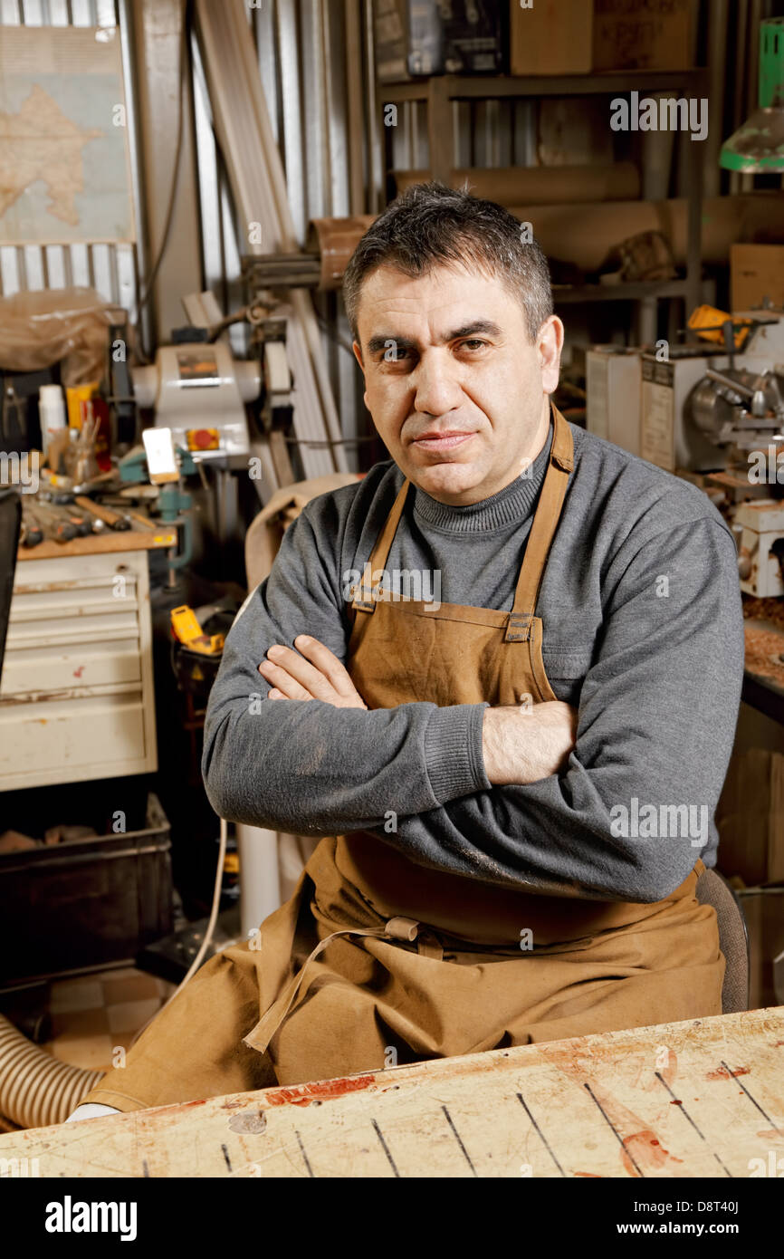 Artisan at workbench arms folded Stock Photo Alamy