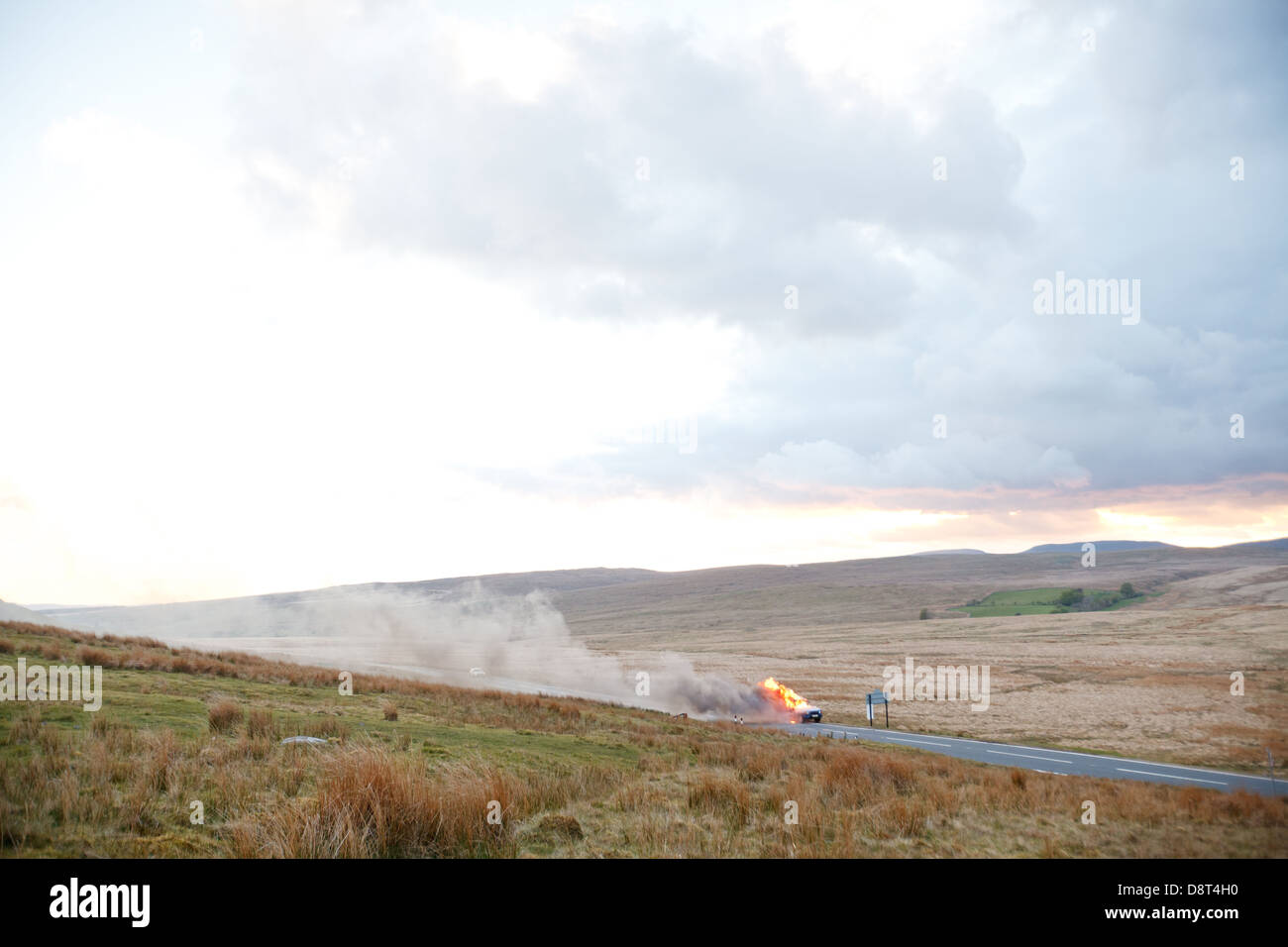 A landrover discovery catches fire on the A4059 between Hirwaun and Brecon. The vehicle burns as the sun sets over the hills. Stock Photo