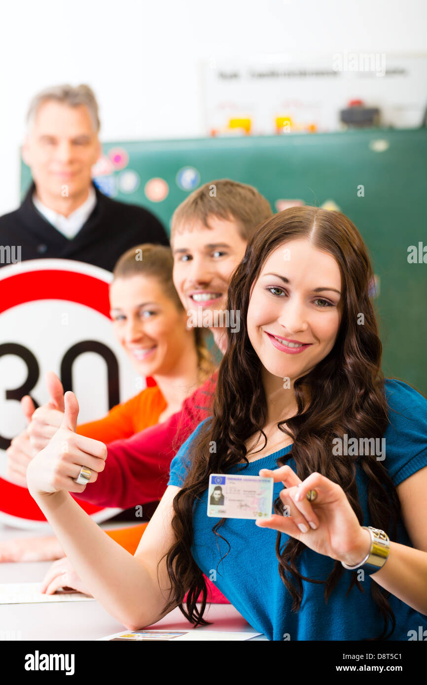 Driving school - driving instructor in his class and a female student driver looking in the Camera Stock Photo
