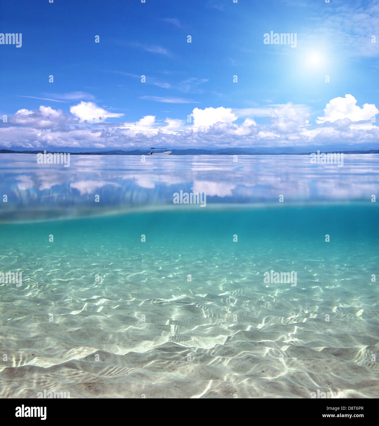 Split view over and under water in the Caribbean sea with clouds reflected on surface and a sandy seabed Stock Photo