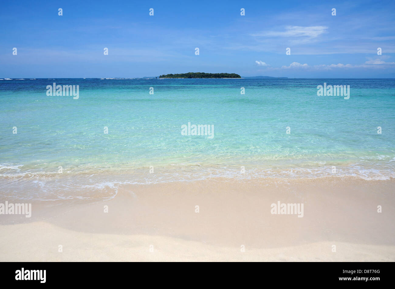 Tropical sandy beach shore with turquoise water and an island at the horizon, Caribbean sea Stock Photo