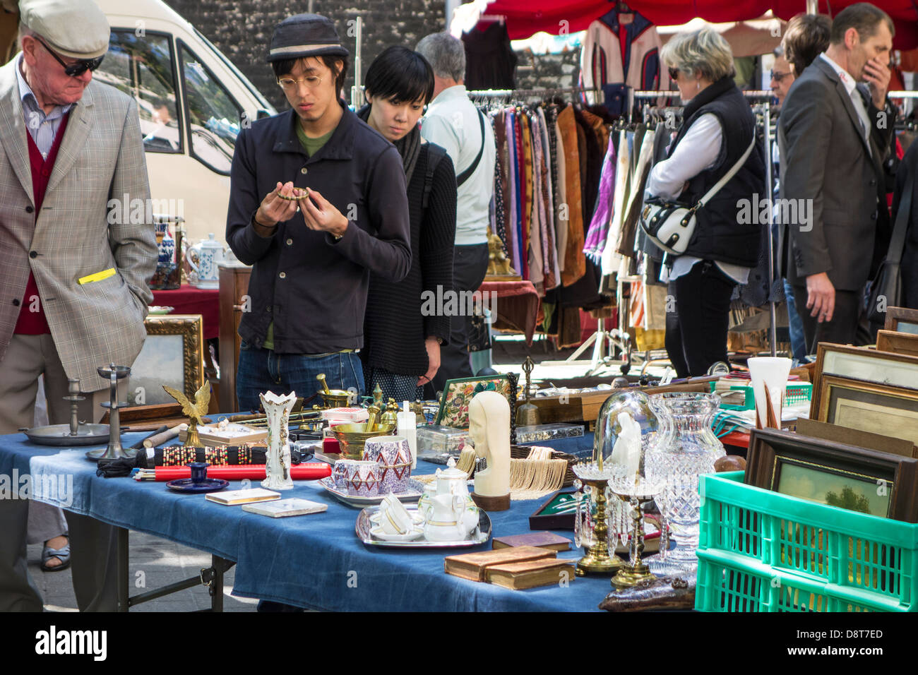 Japanese tourists looking at bric-a-brac and antiques for sale at flea market in town Stock Photo