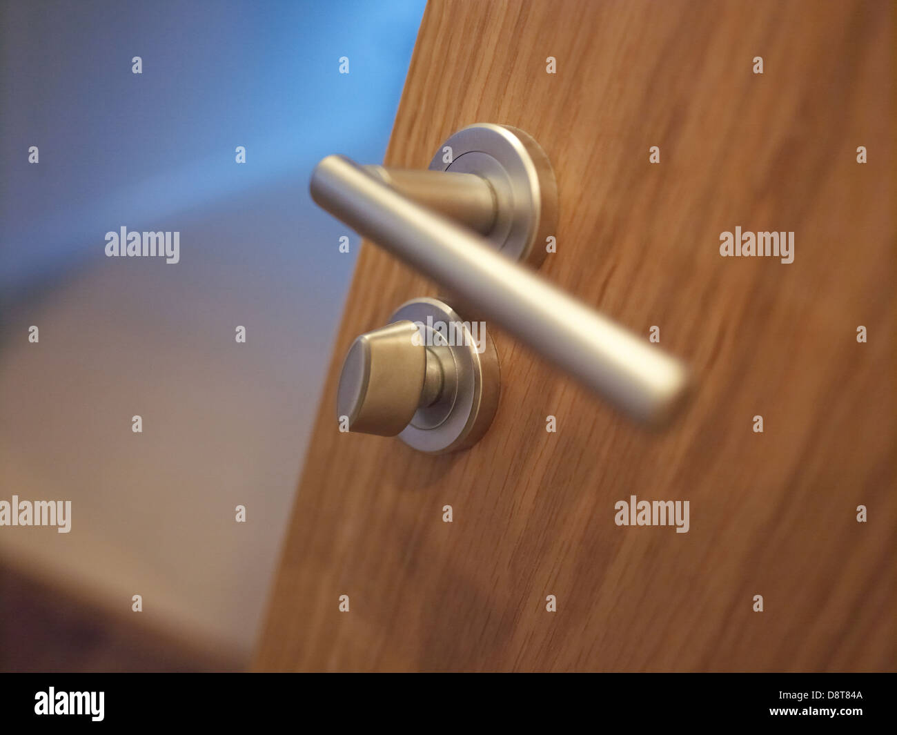 silver door handle and lock on an open brown wood door Stock Photo