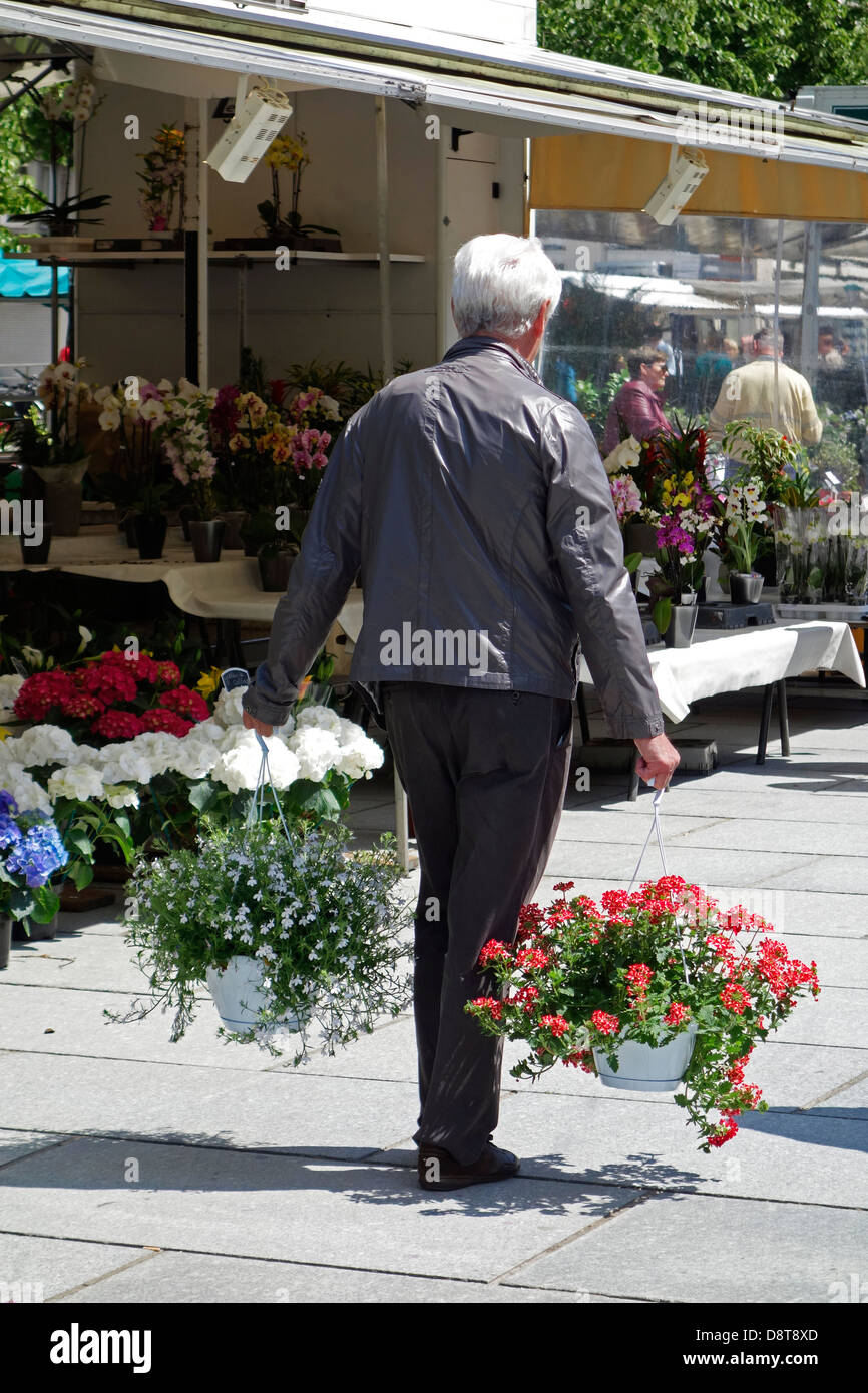 Man walking along stalls with colourful flowers bought at flower market in spring Stock Photo