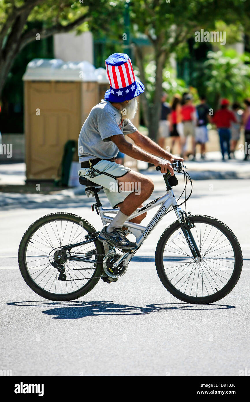 Man wearing a Starts and Stripes hat whilst cycling in downtown Sarasota Florida Stock Photo