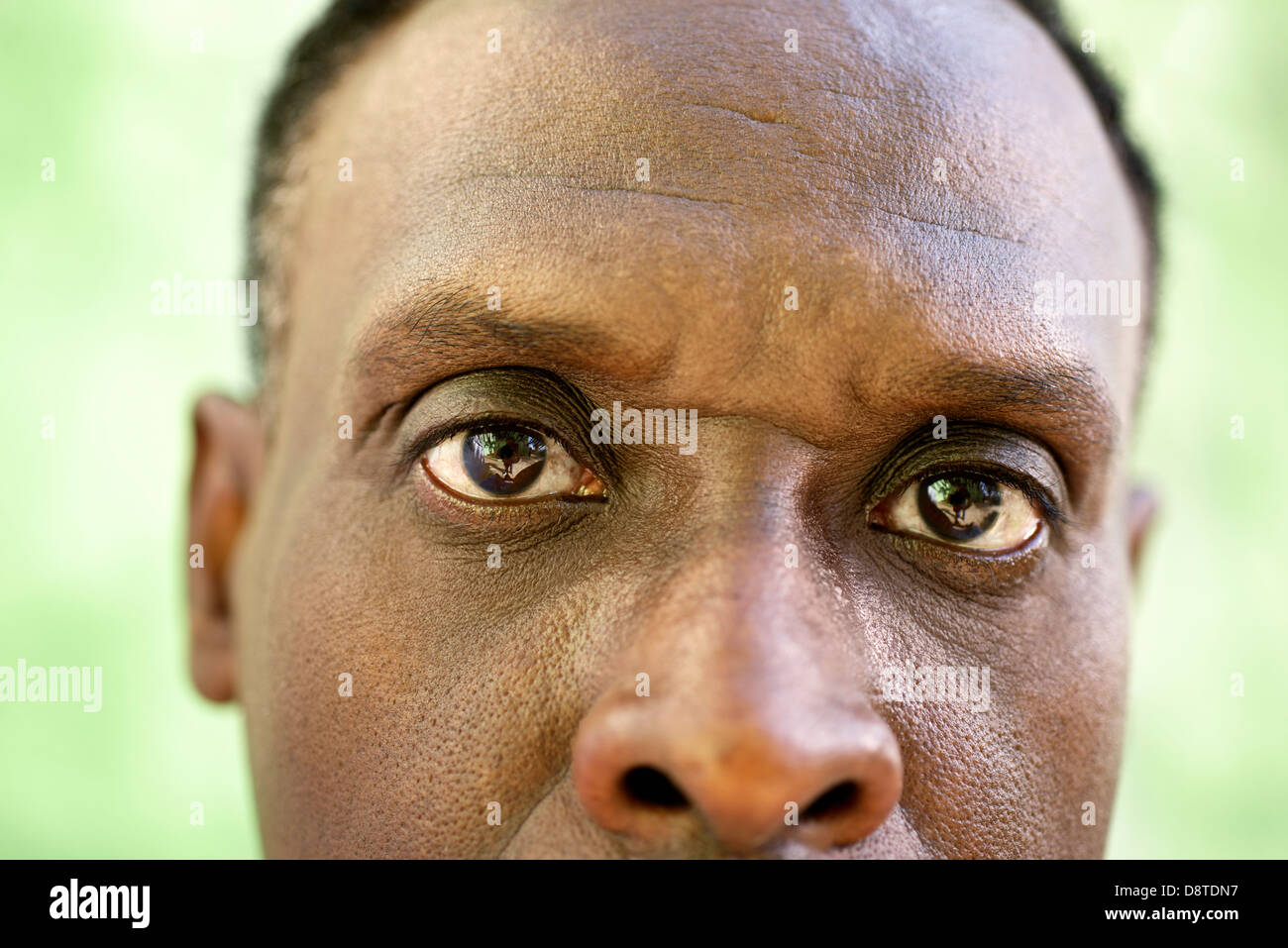 Elderly people and emotions, portrait of serious senior african american man looking at camera against green wall Stock Photo