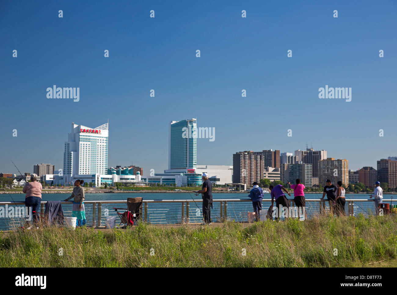 People fish in the Detroit River along the Detroit Riverwalk in Milliken State Park. Stock Photo