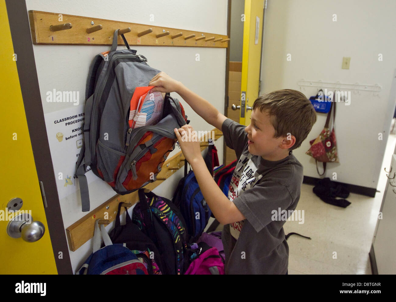 male 7 year old first grade student takes project out of backpack in elementary school classroom in Texas Stock Photo