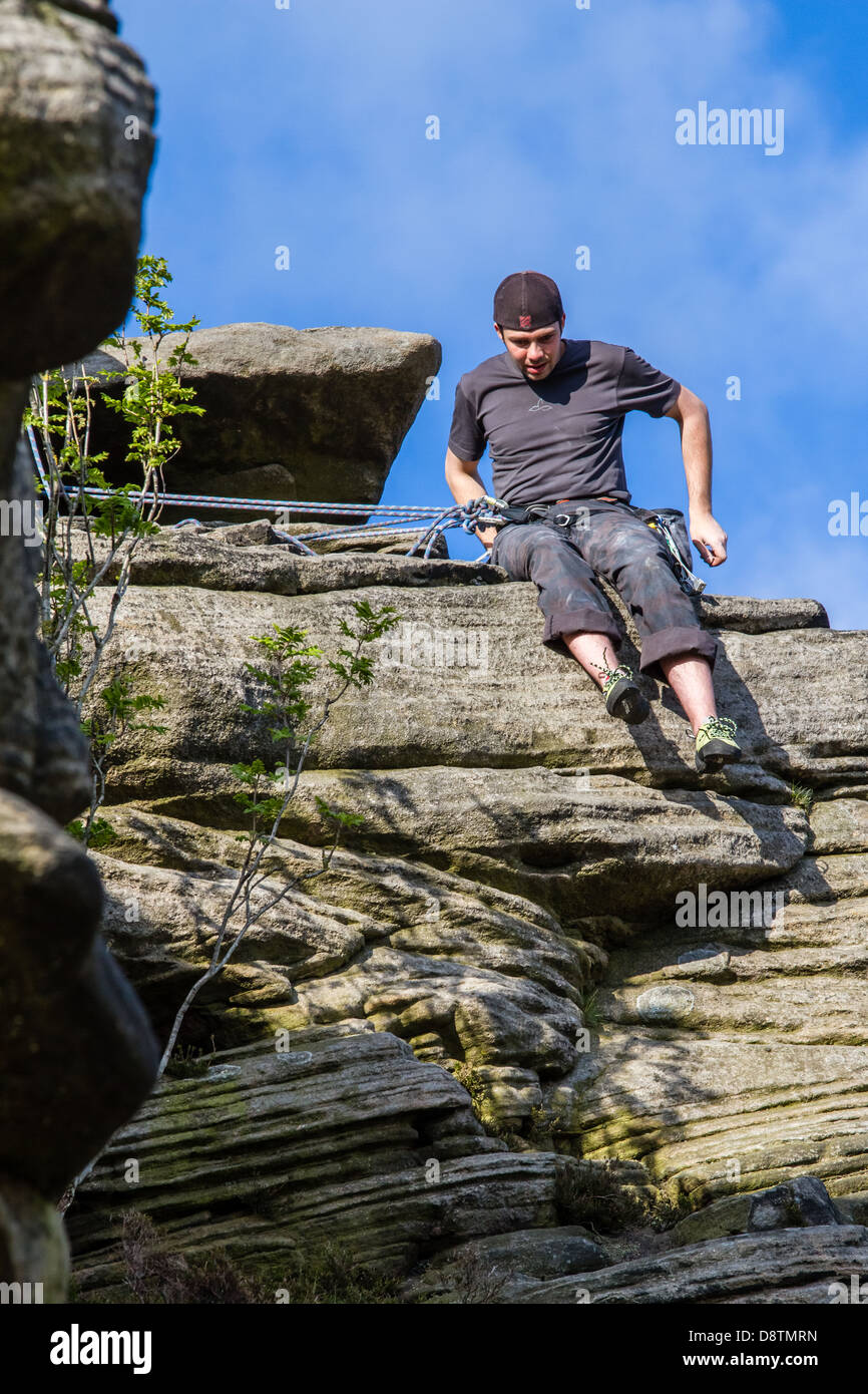 Rock climber person belaying against blue sky at Stanage Edge Stock