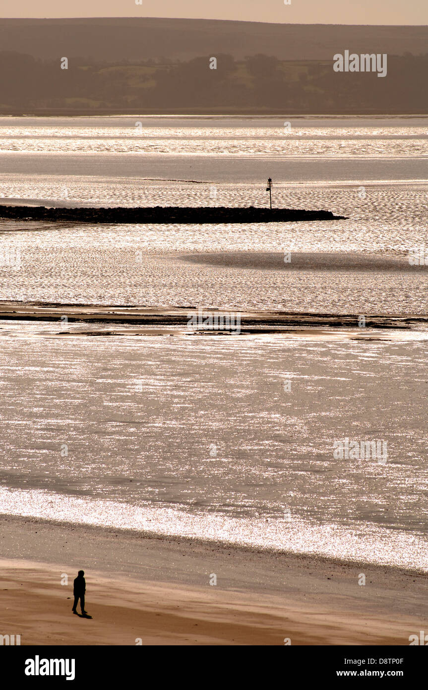 man walking alone on a beach in Llanelli, south wales looking thoughtful Stock Photo