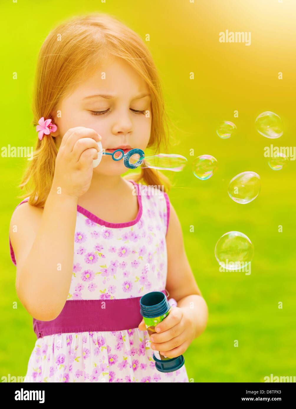 Closeup portrait of cute baby girl blowing soap bubbles outdoors