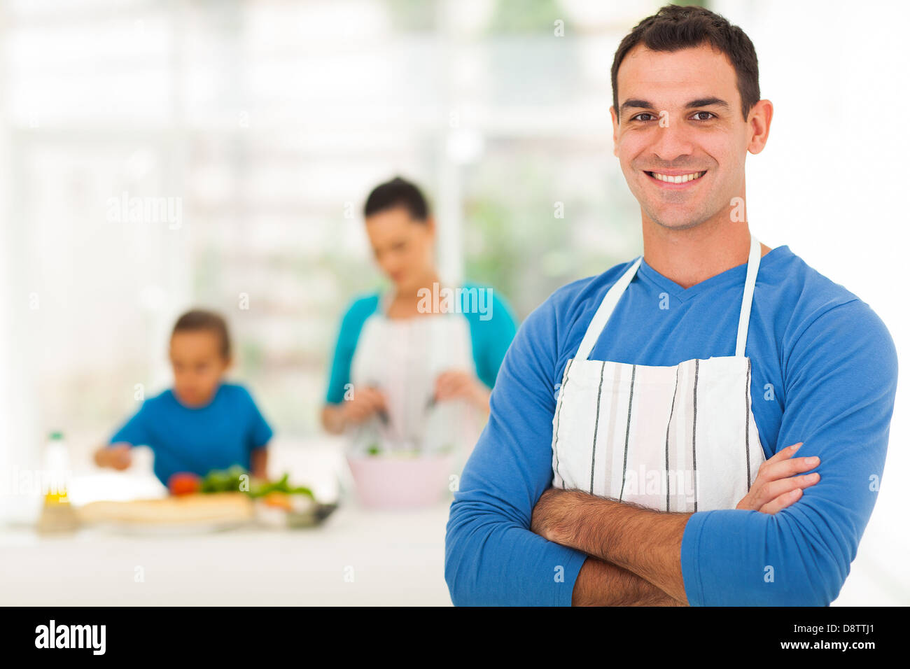 handsome family man standing in front of family in kitchen Stock Photo