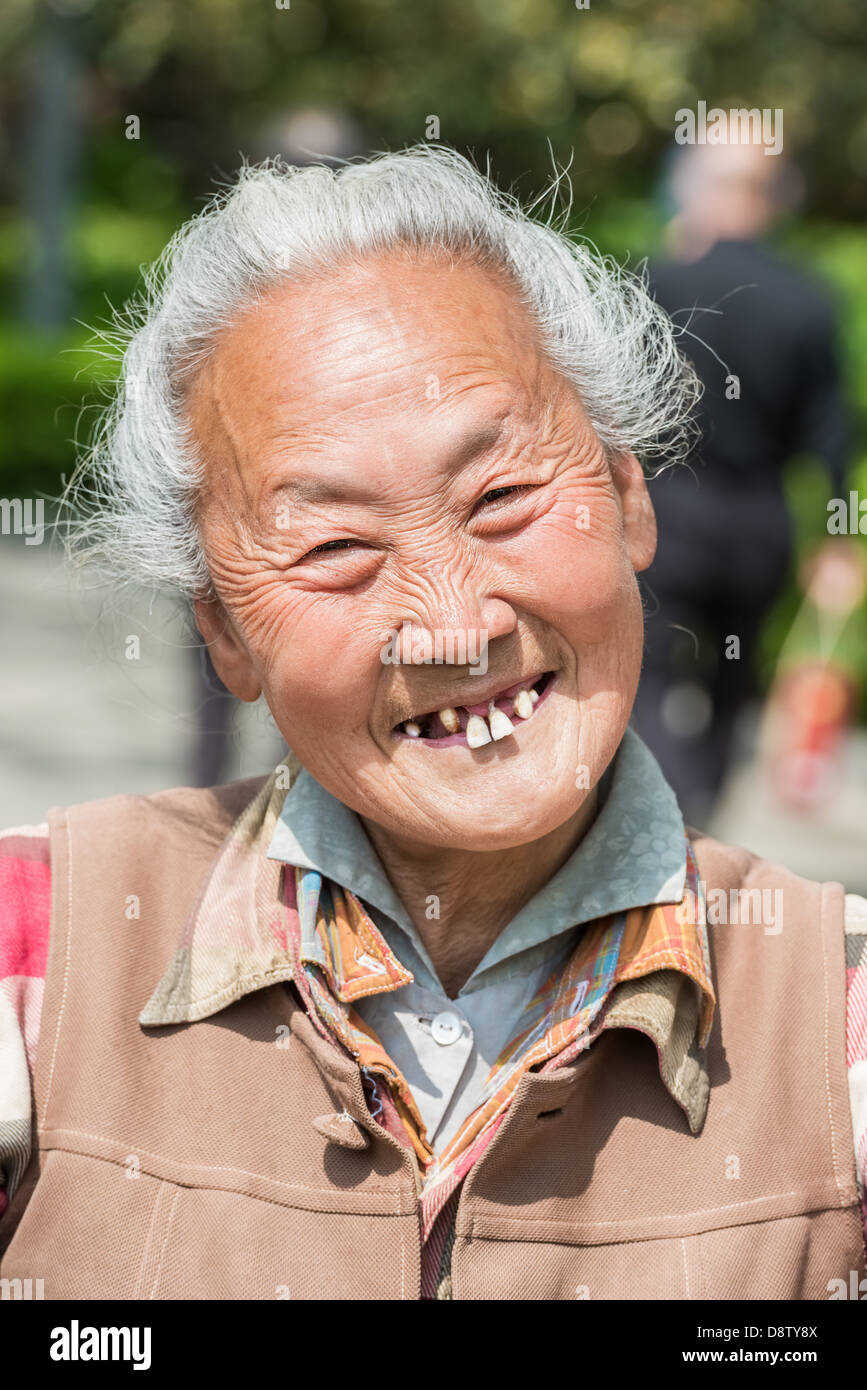 Shanghai, China - April 7, 2013: old chinese woman friendly toothless toothy smiling outddors portrait at the city of Shanghai in China on april 7th, 2013 Stock Photo