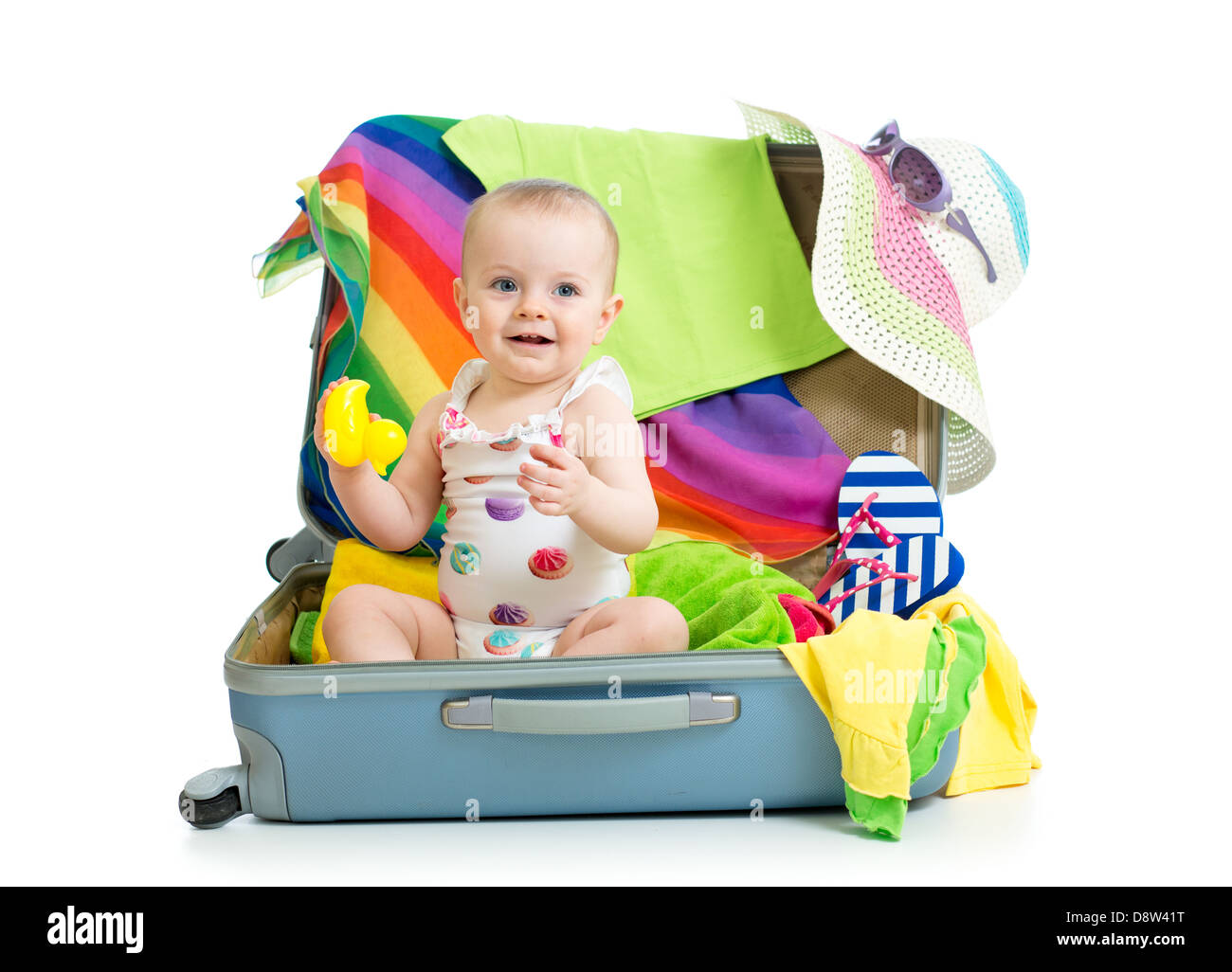Baby girl sitting in suitcase with things for vacation travel Stock
