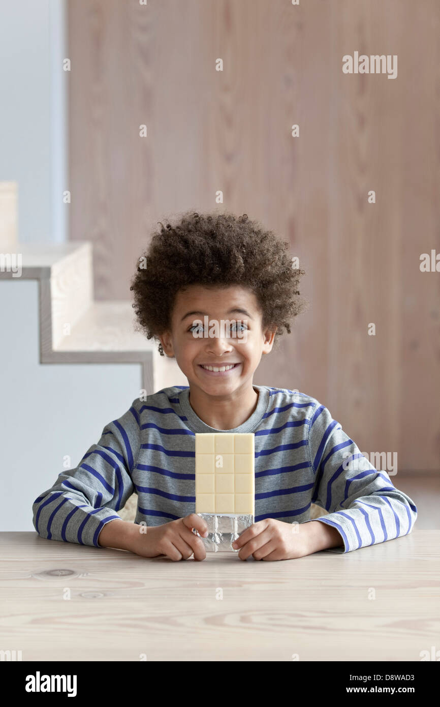 Boy smiling infront of a bar of white chocolate Stock Photo