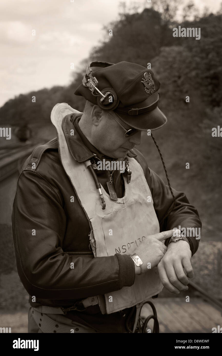 A sepia toned monochrome image of a reenactor dressed as a WW2 bomber pilot looking at his watch. Stock Photo