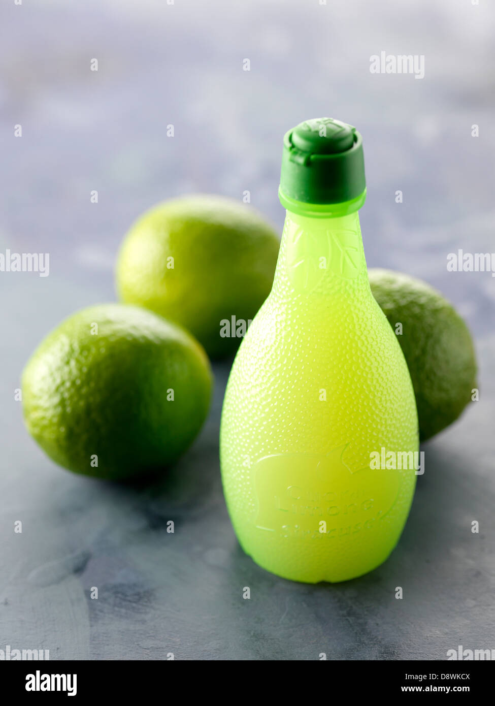 Small bottle of lime juice and limes Stock Photo