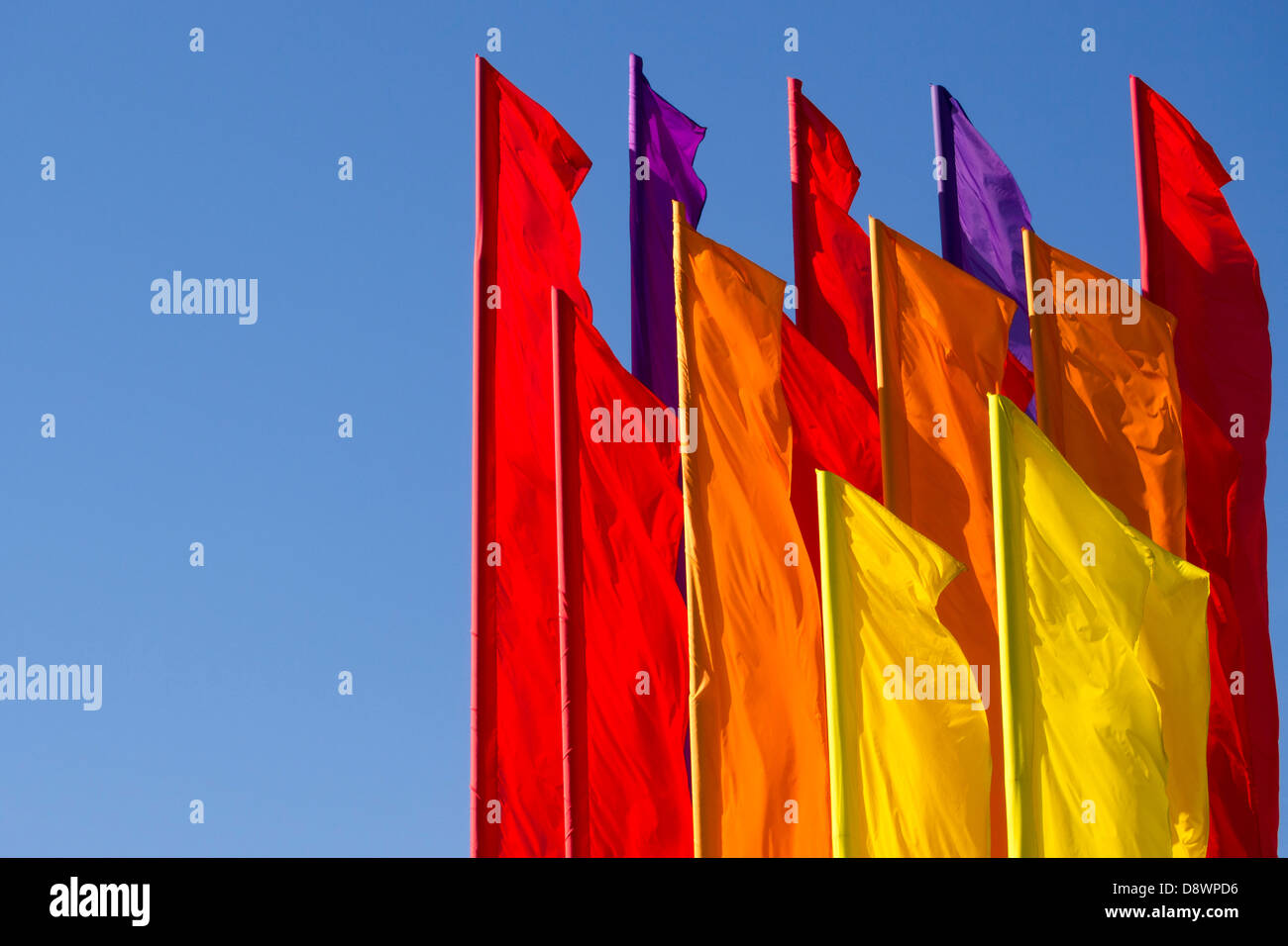 many color flags on the wind with clear blue sky behind Stock Photo
