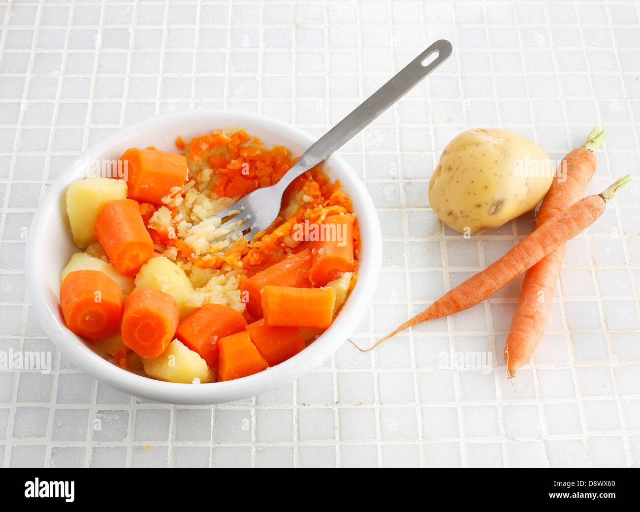 Mashing together the carrots and potatoes Stock Photo Alamy