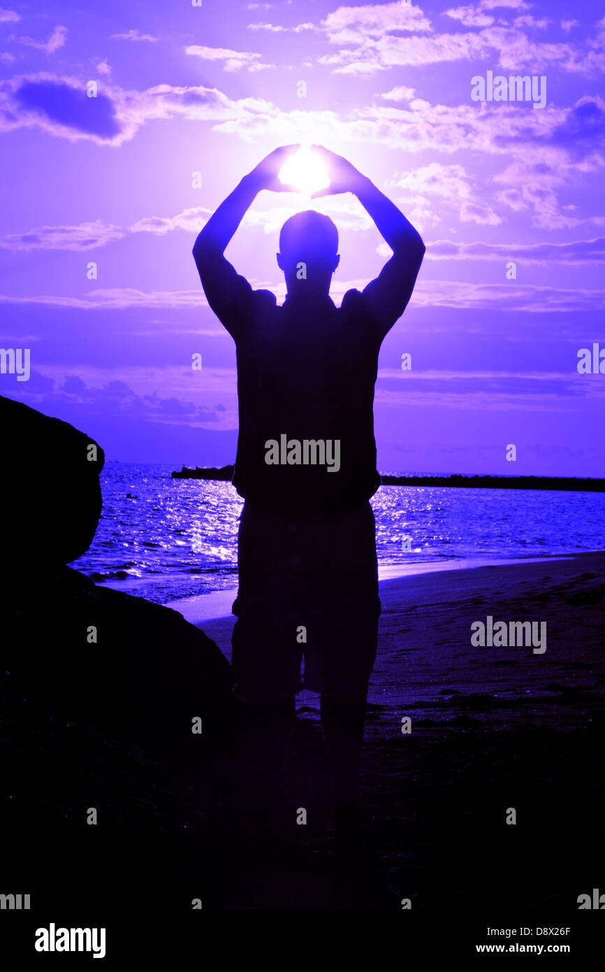 Silhouette of male holding the sun Stock Photo
