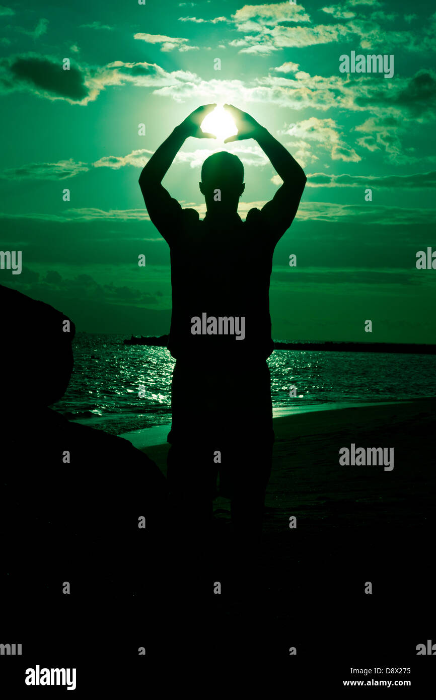 Silhouette of male holding the sun Stock Photo