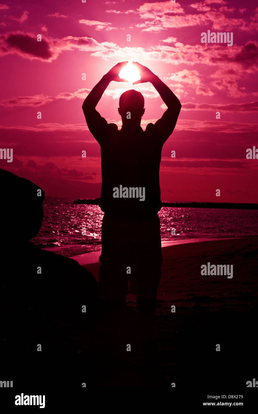 Silhouette of male holding the sun Stock Photo