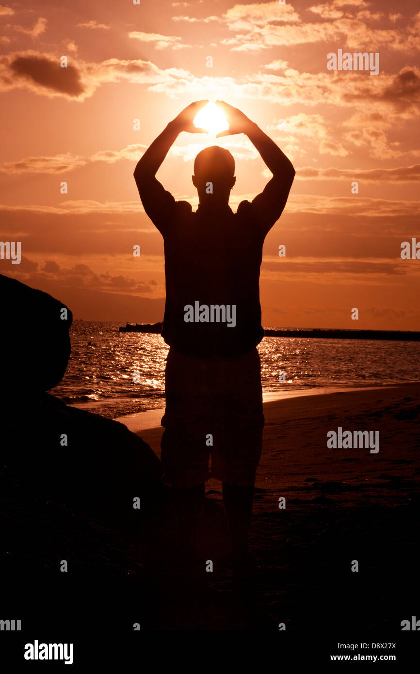 Silhouette of male holding the sun Stock Photo