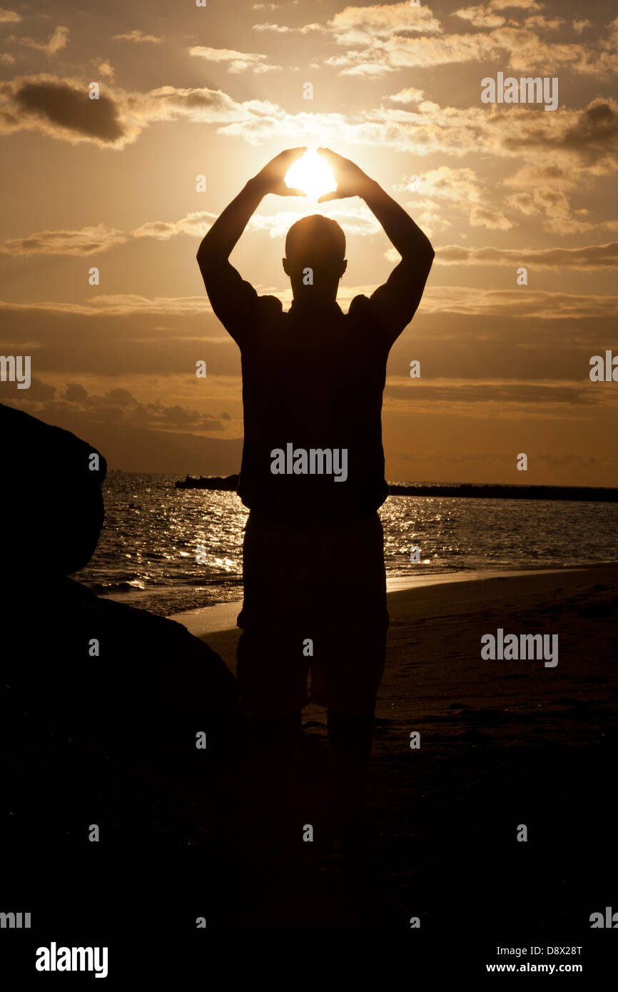 Silhouette of male holding the sun Stock Photo