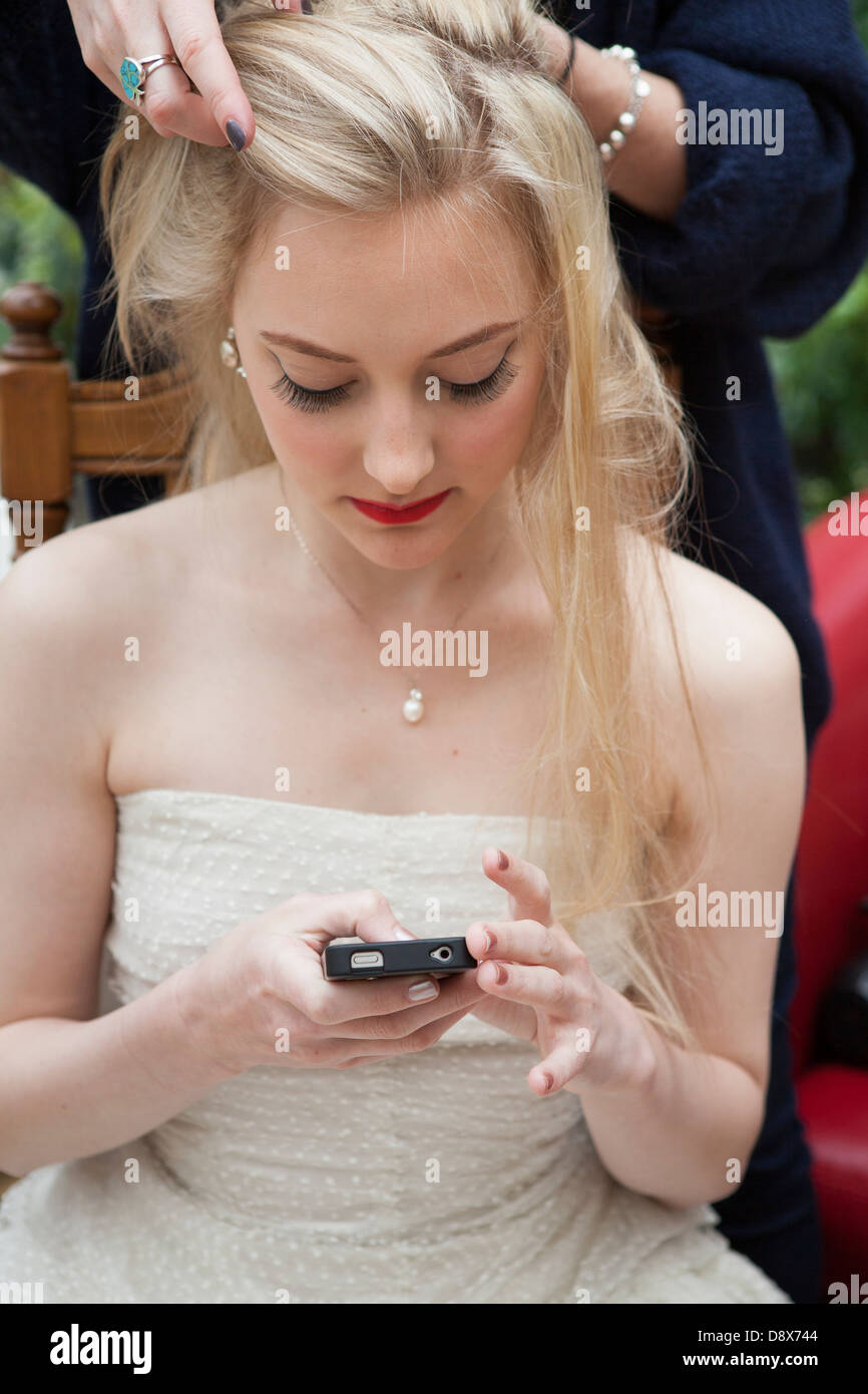 Bride texting ,during make-up Stock Photo