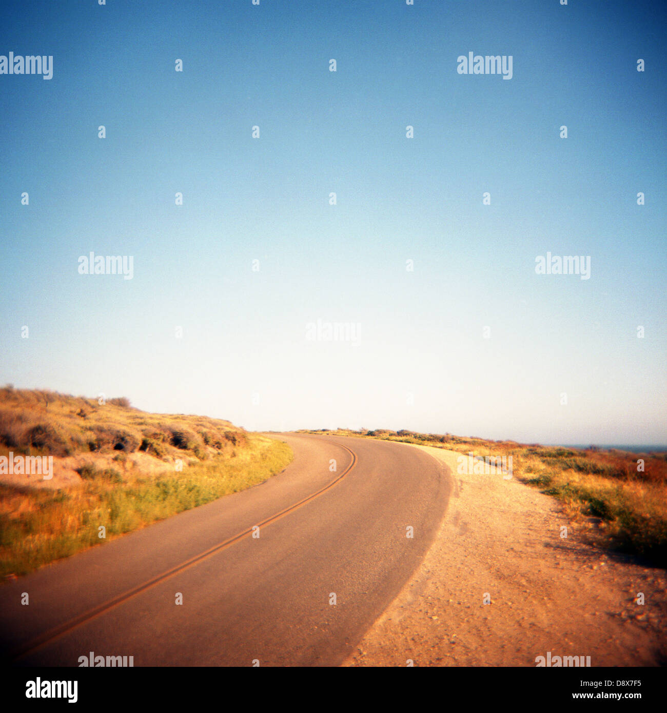 medium format square film photograph of a curved road with blue skies in coastal California Stock Photo