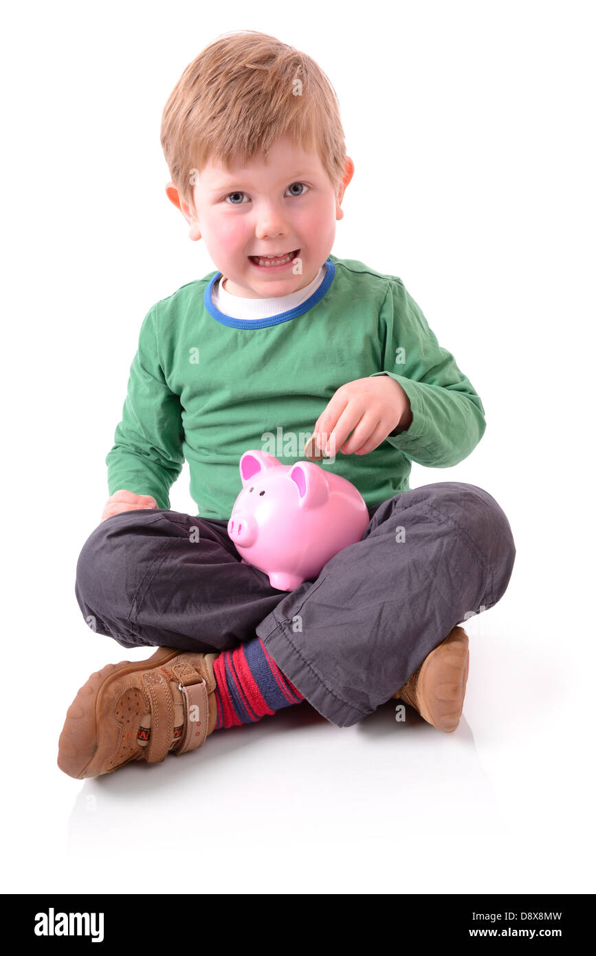 Cute little boy putting a coin into a piggy bank isolated on white ...