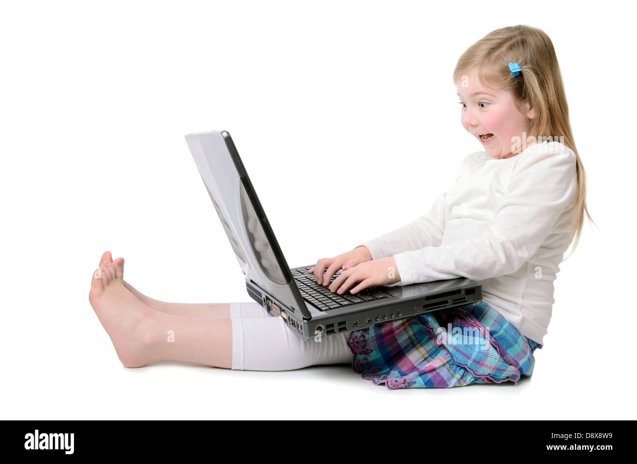 little girl playing with laptop on white floor Stock Photo