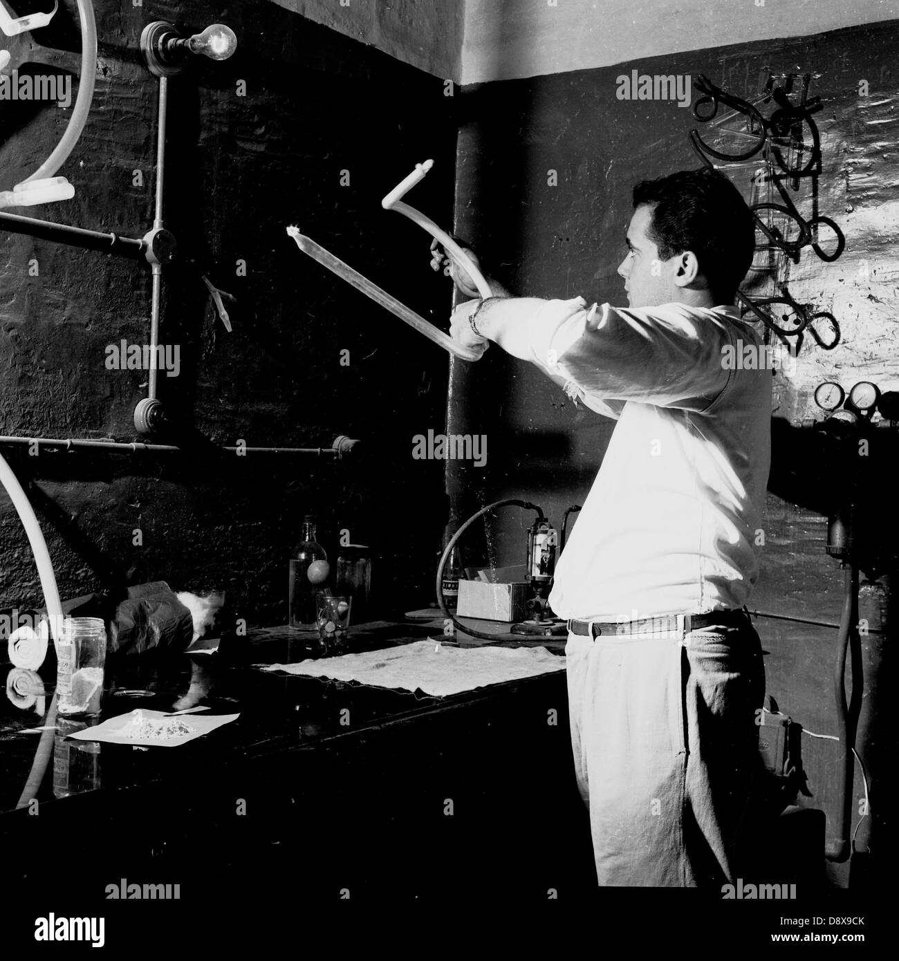 Historical picture from 1950s of a man in workshop bending the luminous tube to make a neon sign. Stock Photo