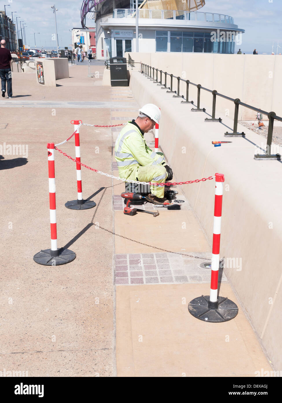 An electrician fitting lights into the pavement edge by the Redcar Sea Wall Stock Photo