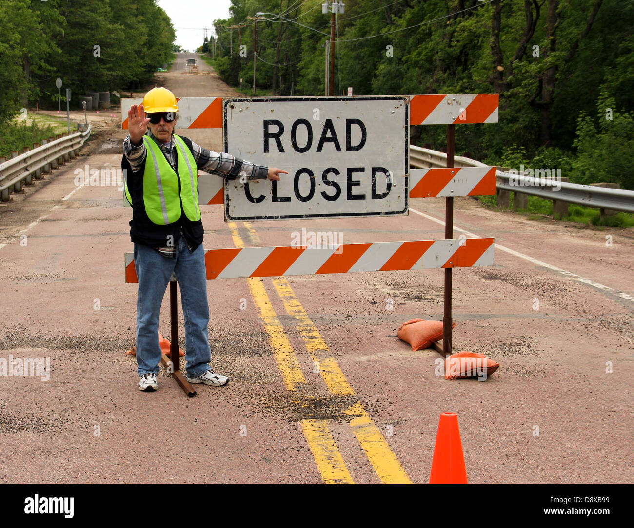 flag man points to a road closed sign on a highway Stock Photo