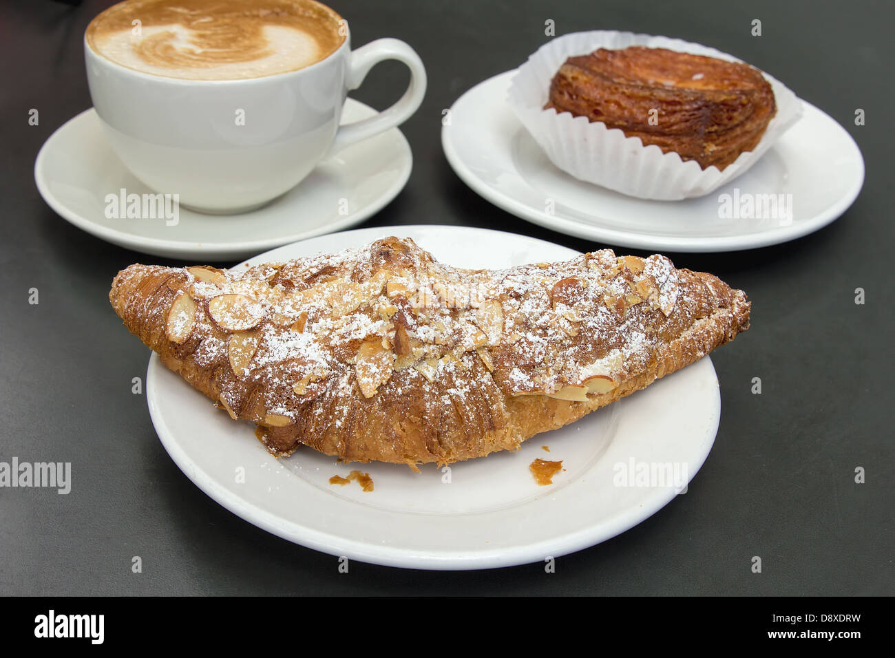 Almond Croissant French Pastry on White Plate with Cup of Latte Stock Photo