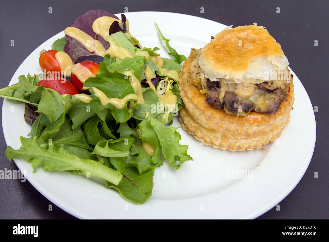 Chicken Pot Pie with Leafy Green Vegetables Tomatoes and Salad Dressing Stock Photo