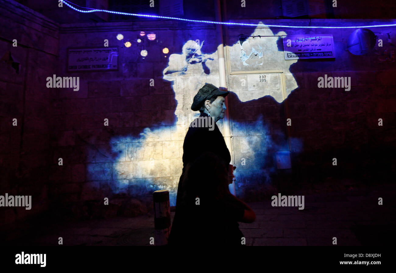 A pedestrian pass a light show projected over the Greek Orthodox Patriarchate building in the Christian Quarter during the Jerusalem Festival of Lights on June 05 2013. The festival is held annually around Jerusalem's old city with special effects illuminating historical sites. Stock Photo