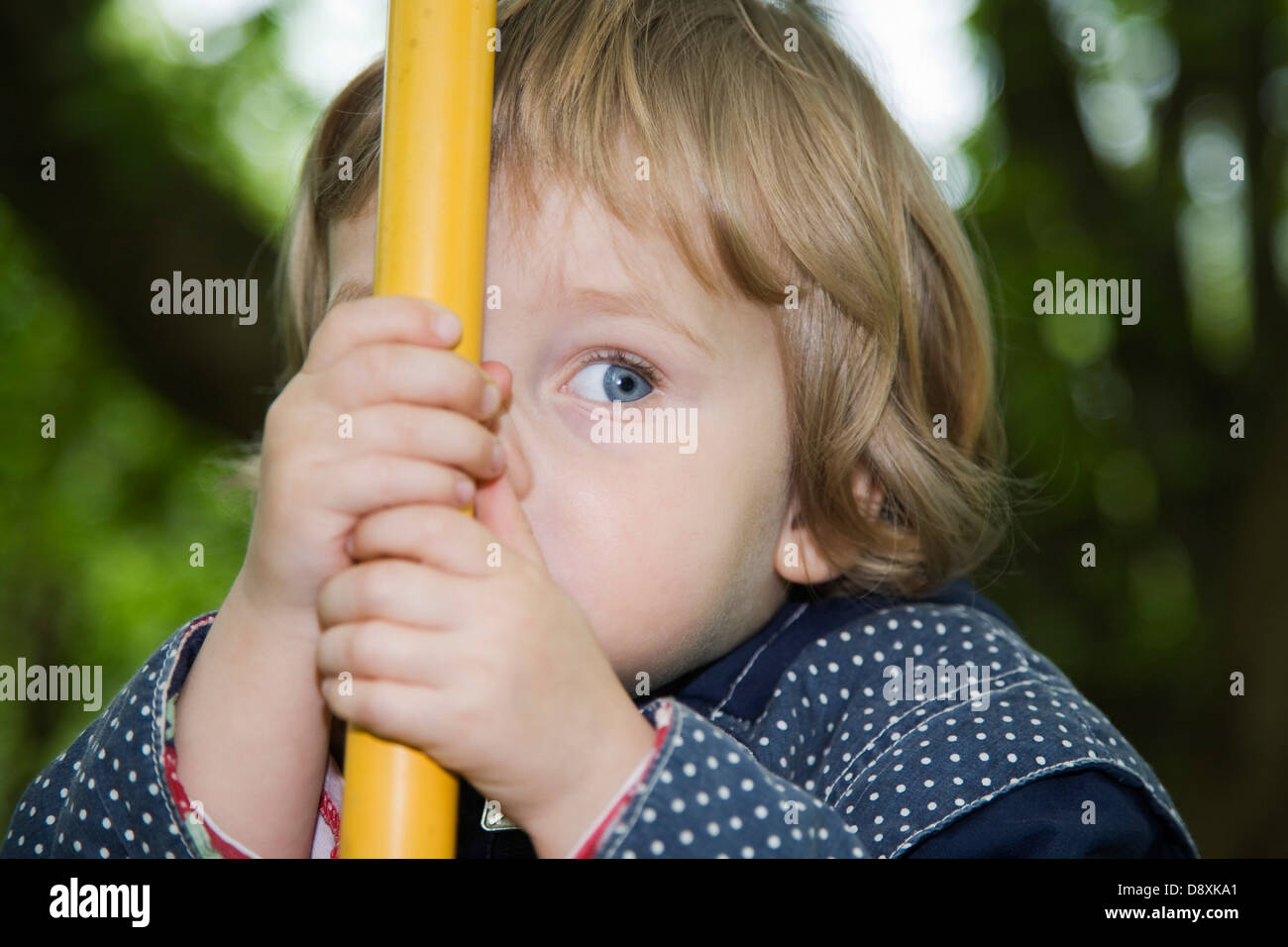 Three year-old girl hides behind a bar Stock Photo