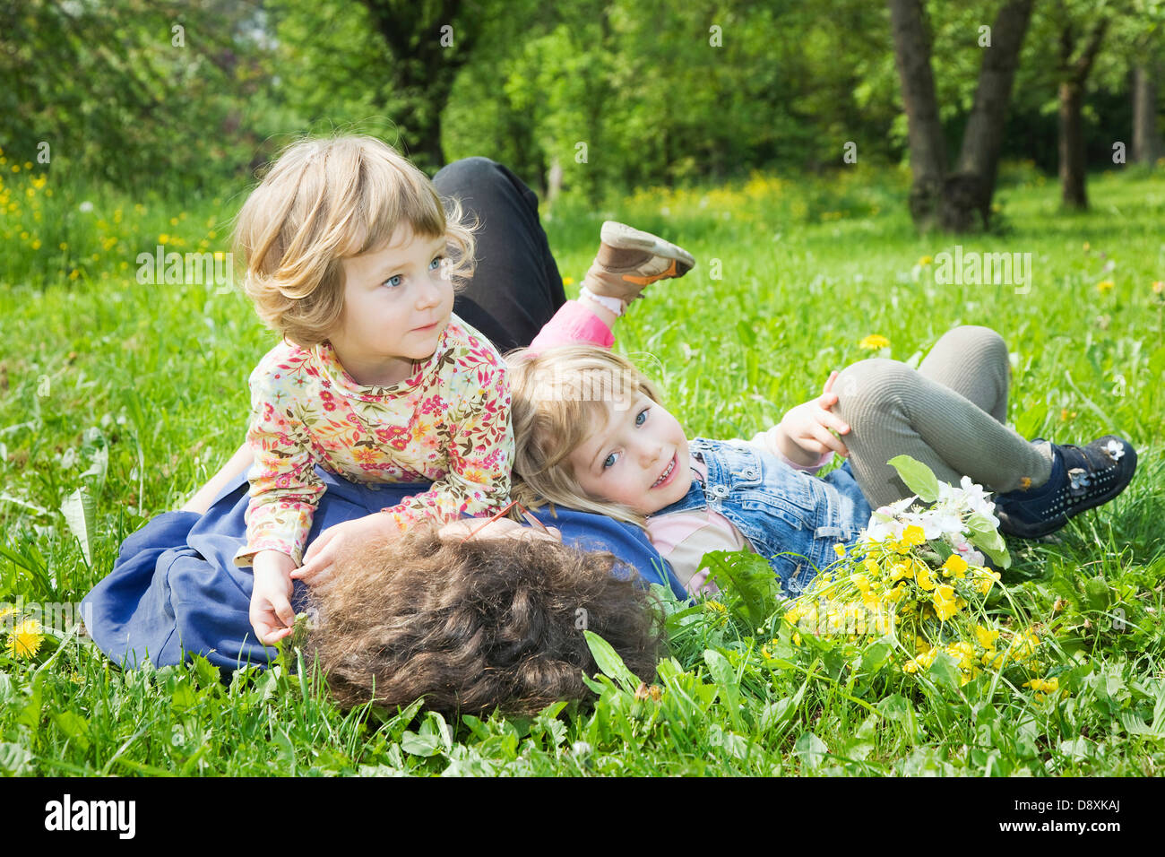 Woman lying with her two daughters on a meadow in spring Stock Photo