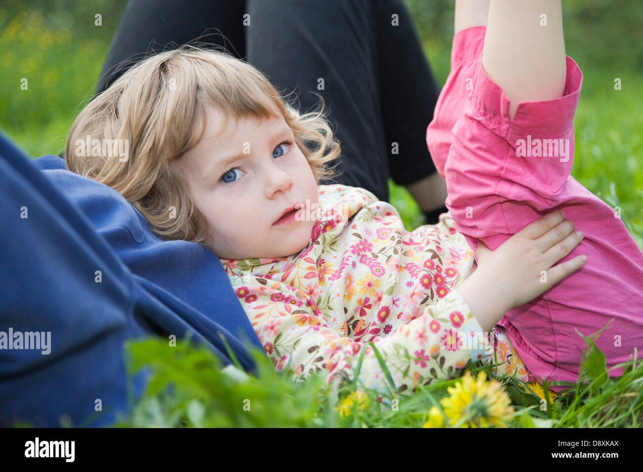 Three year-old girl leaning on his mother's belly stretching her legs Stock Photo