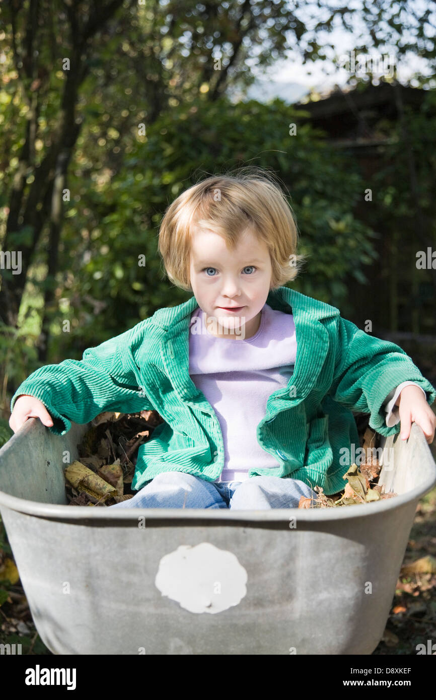 Three year-old girl sitting in a bathtub filled with leaves Stock Photo