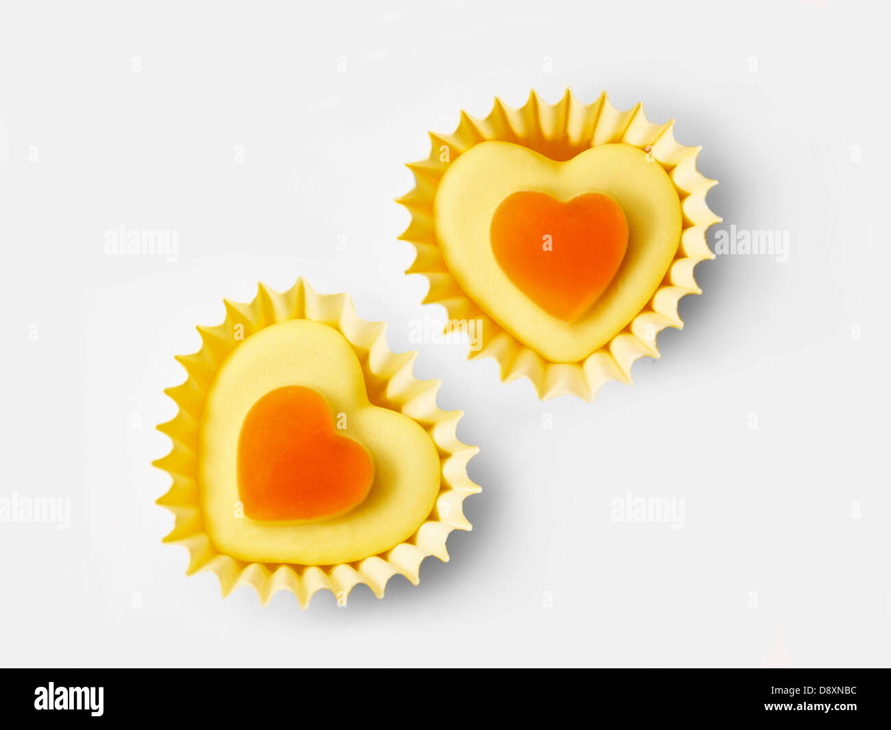 Small orange candies in heart-shaped paper cups Stock Photo - Alamy