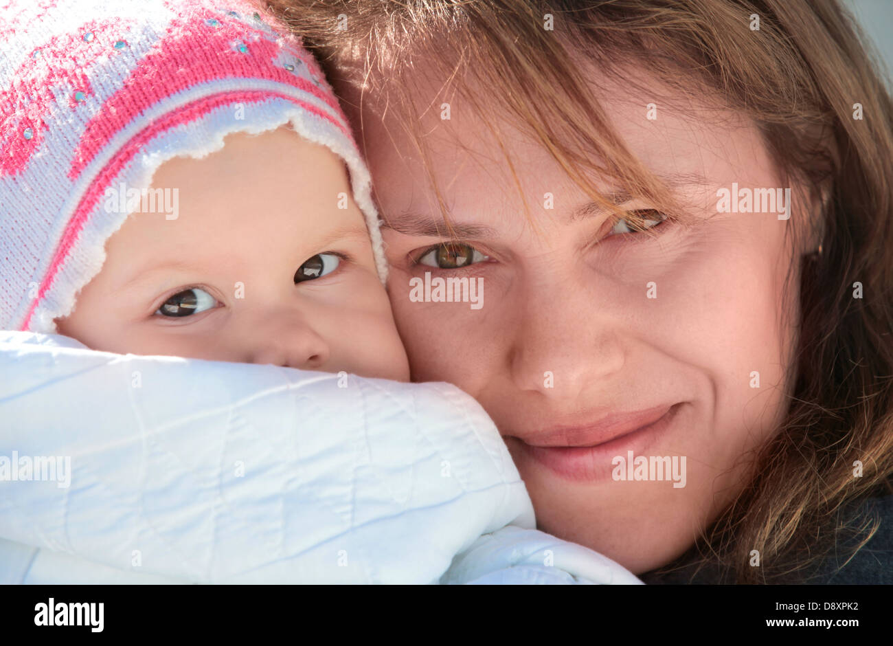 Young European woman holds her sleepy baby in blanket. Outdoor closeup portrait Stock Photo