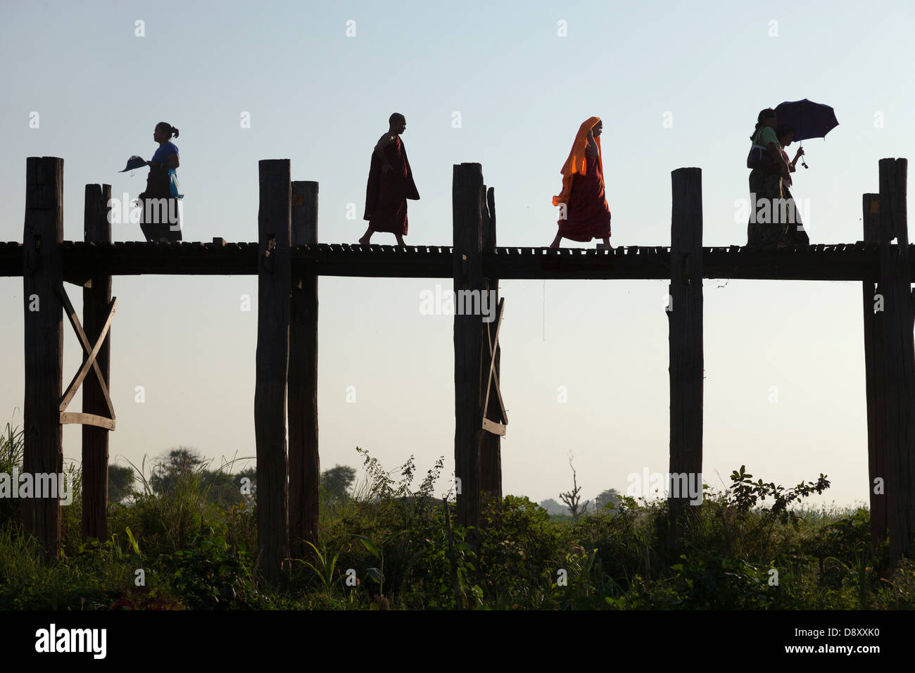 Women and monks Crossing U Bein Teak Bridge across Taungthaman Lake ...
