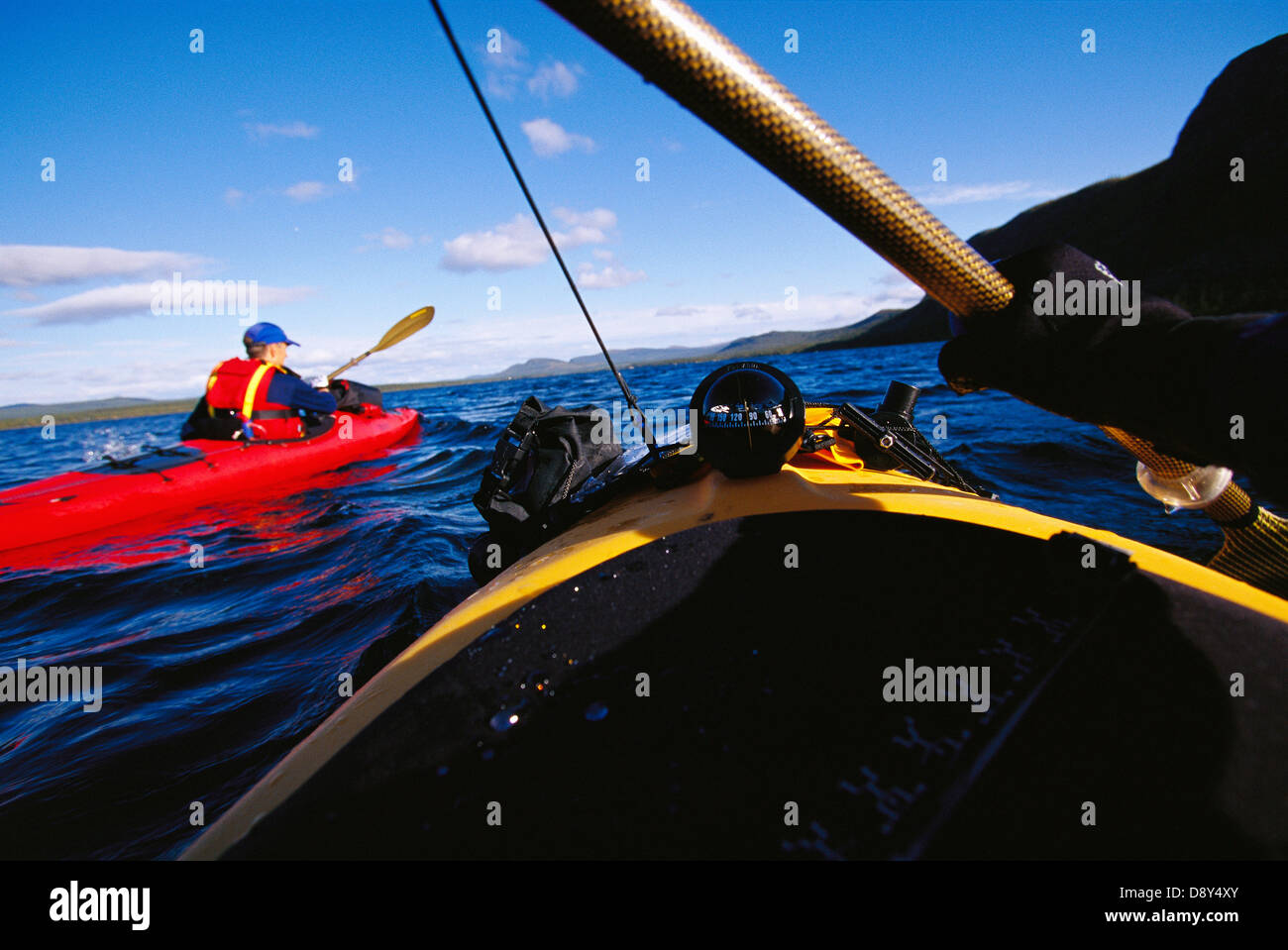 A man paddling a kayak seen from the front of another kayak. Stock Photo