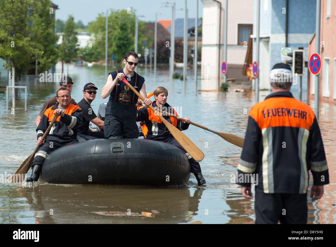 Rescue workers row in an inflatable raft through the flooded streets ...