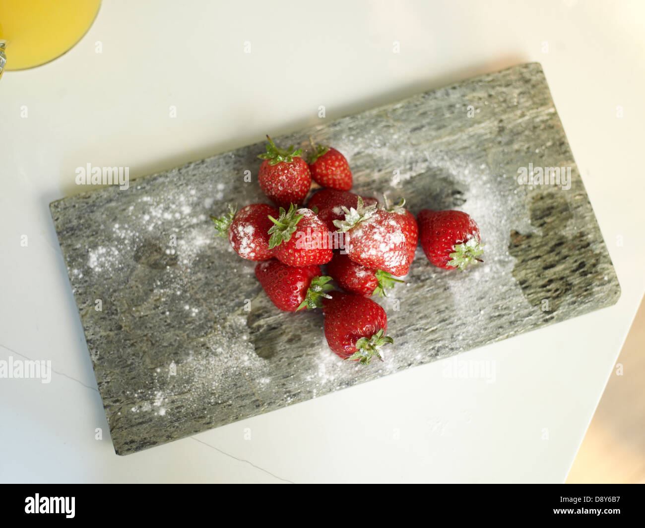 A plateful of strawberries placed on a wooden board, coated with dusting. Stock Photo