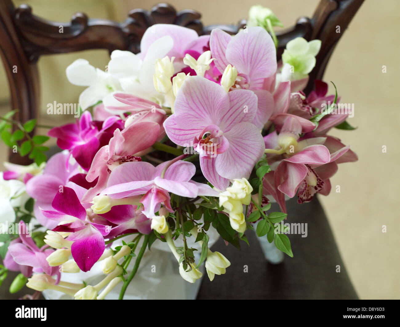 A spray of wedding flowers containing mixture of pink and white orchids, placed on a wooden table. Stock Photo